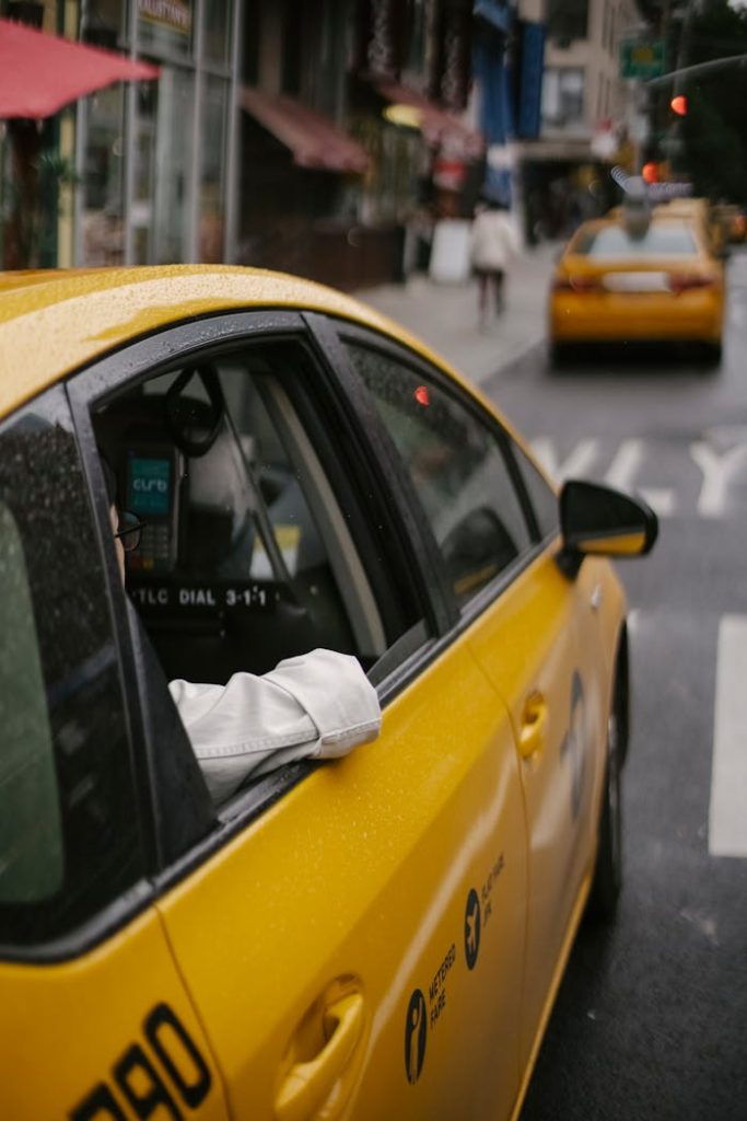 pexels-photo-5835288 From above of unrecognizable person in white shirt sitting in modern yellow cab on asphalt roadway on urban background in town at daytime